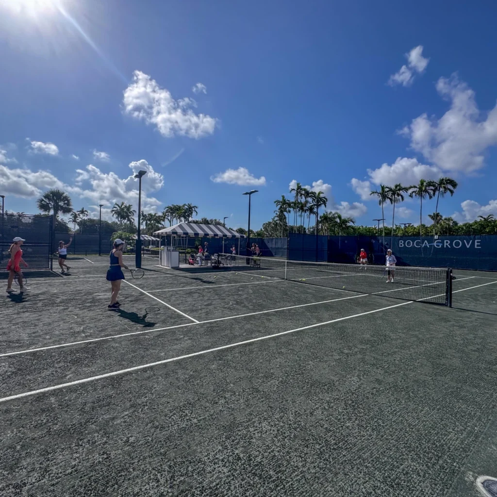 Members playing doubles tennis on Har-Tru clay courts at Boca Grove in Boca Raton.