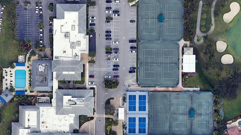 Aerial view of Boca Woods Country Club featuring the clubhouse, Har-Tru tennis courts, pickleball courts, and championship golf course in Boca Raton.