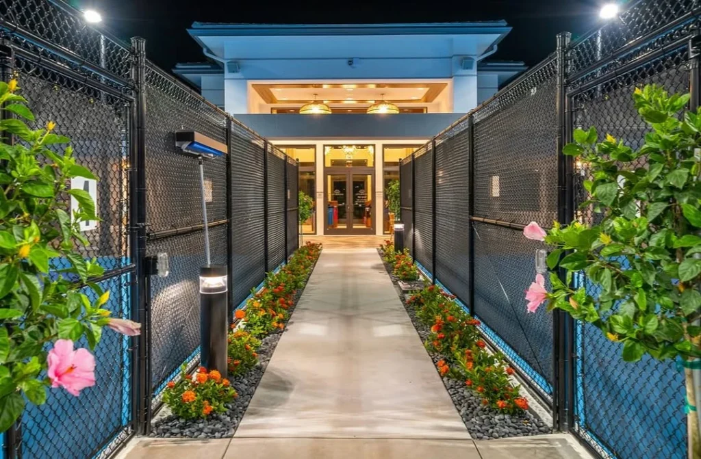 Lit walkway entrance between tennis courts leading to Lotus Edge clubhouse at night