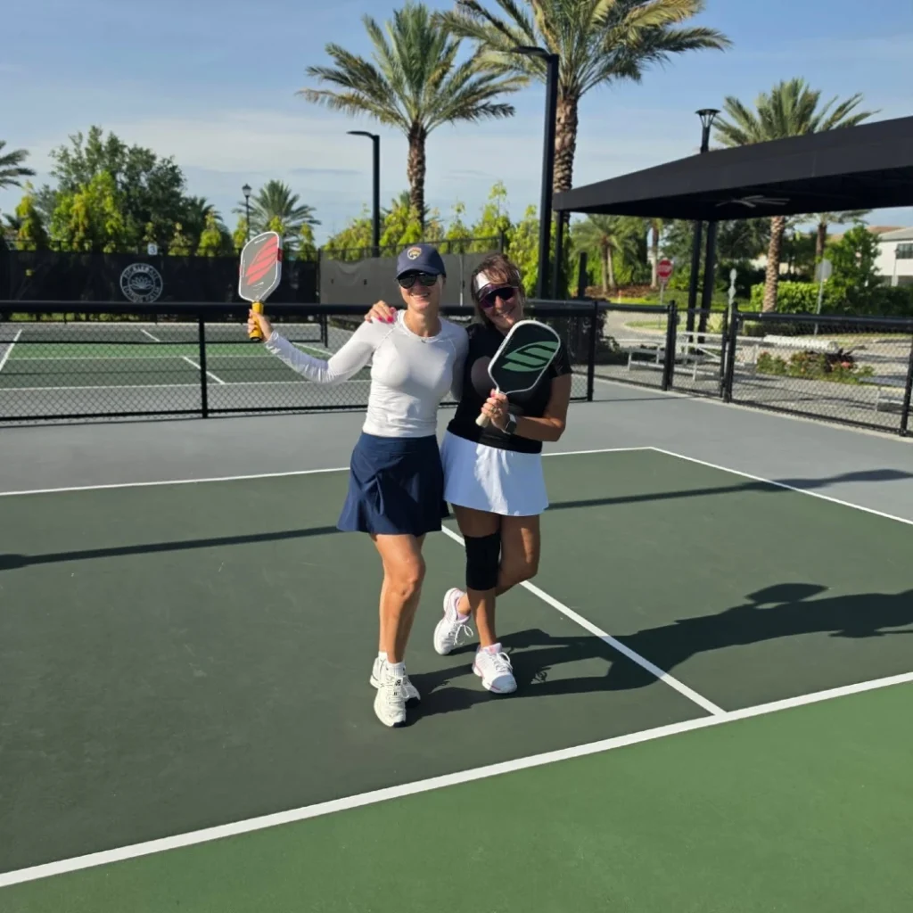 Two players on Lotus Palm pickleball courts with Lotus Palm Pickleball Center signage