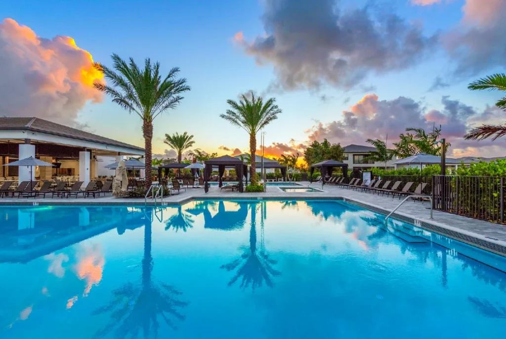 Lotus Palm resort-style pool at sunset with cabanas and palm trees