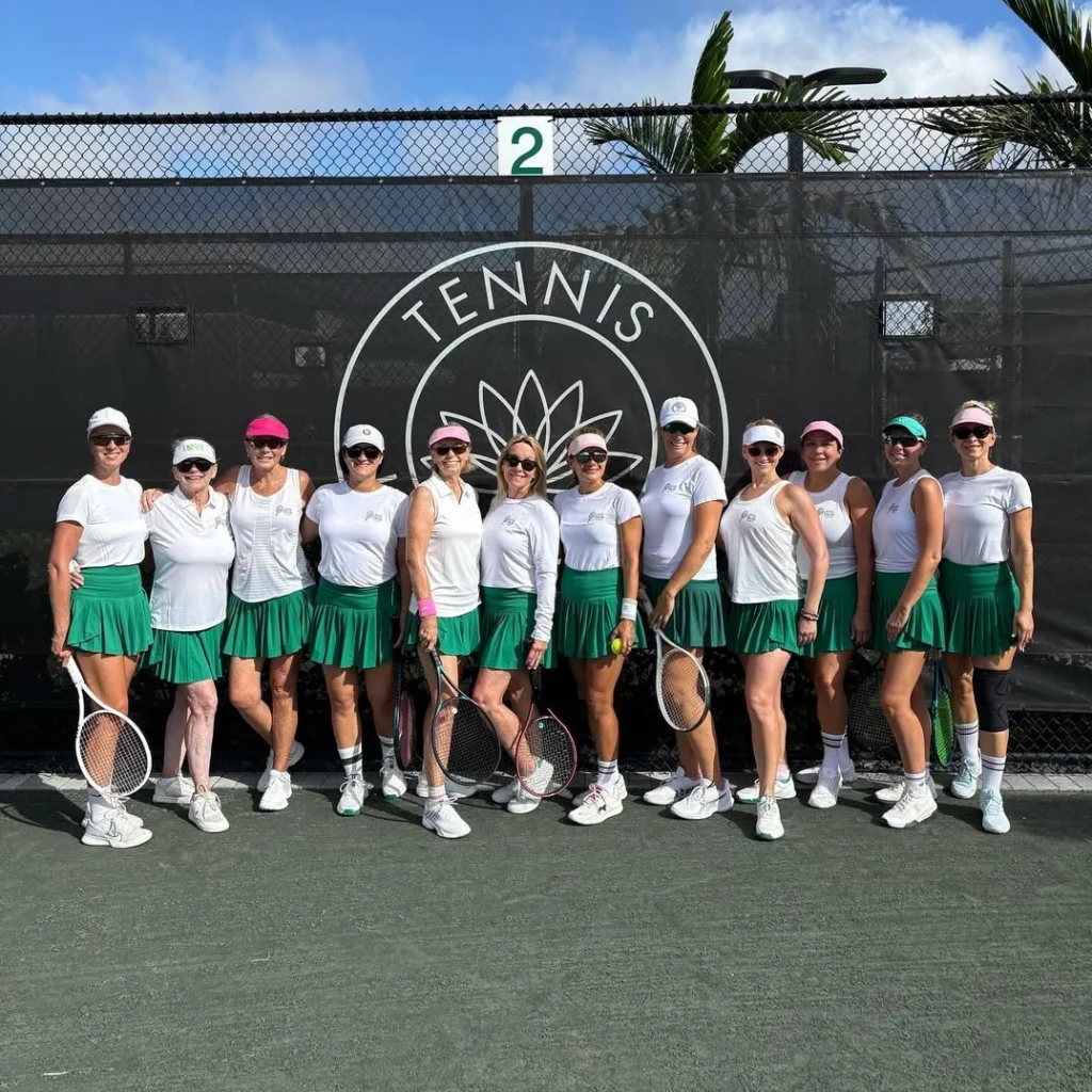 Lotus Palm women's tennis team in matching uniforms in front of court branding