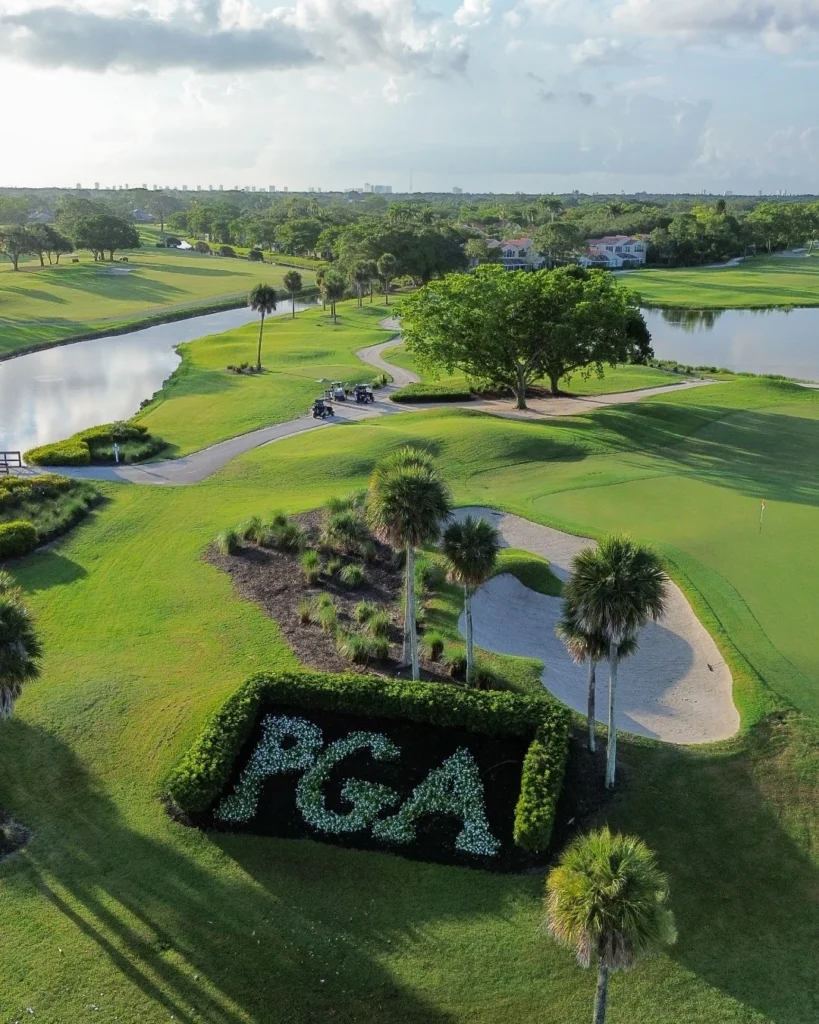 Aerial view of PGA National championship golf course with PGA logo in turf, sand bunkers, and lake in Palm Beach Gardens Florida