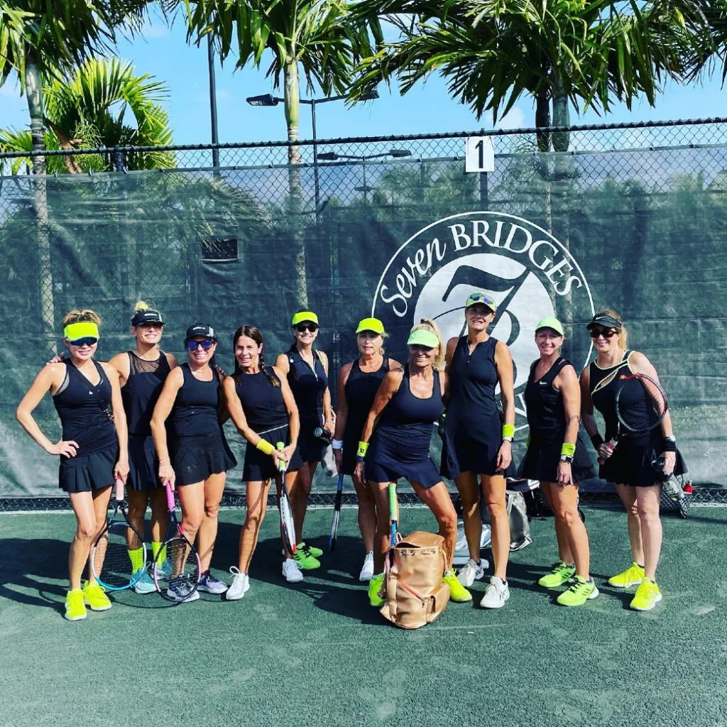 Seven Bridges women's tennis team in matching uniforms in front of court branding