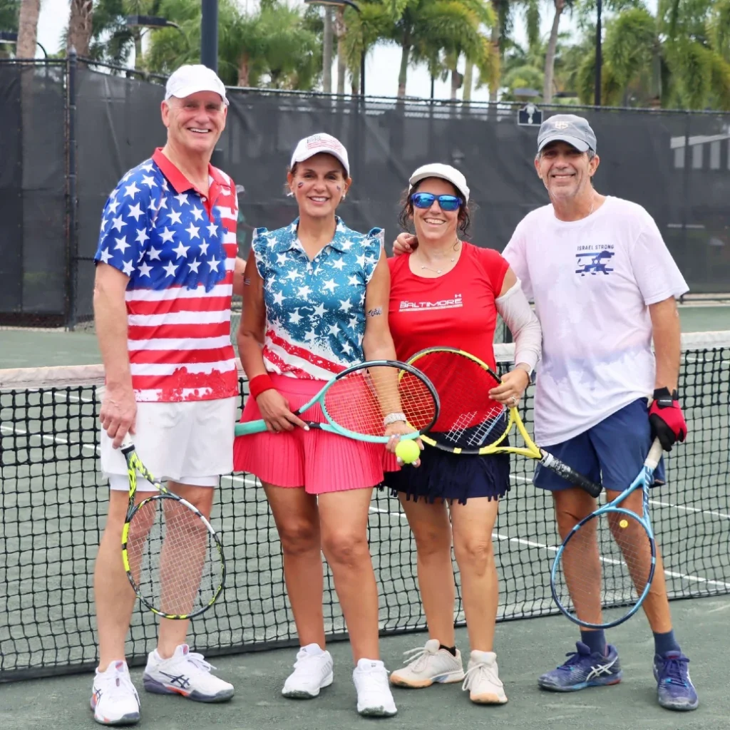 Four members in patriotic attire at the net during a themed tennis social event at The Club at Ibis