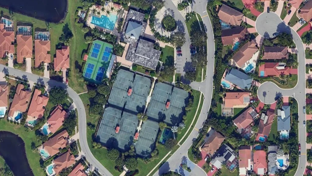 Aerial view of Newport Bay Club showing the tennis complex, pickleball courts, clubhouse, pool, and surrounding homes in Boca Raton