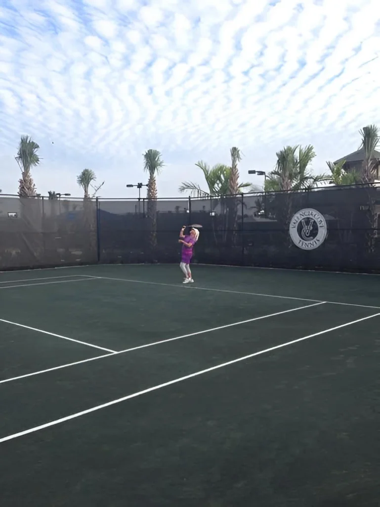 Resident serving on a Har-Tru clay tennis court at Valencia Cove in Boynton Beach