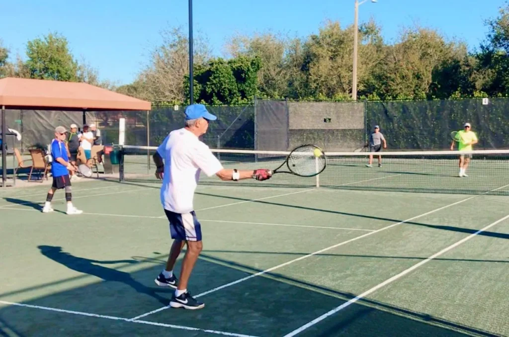 Residents playing doubles tennis on Har-Tru clay courts at Valencia Palms