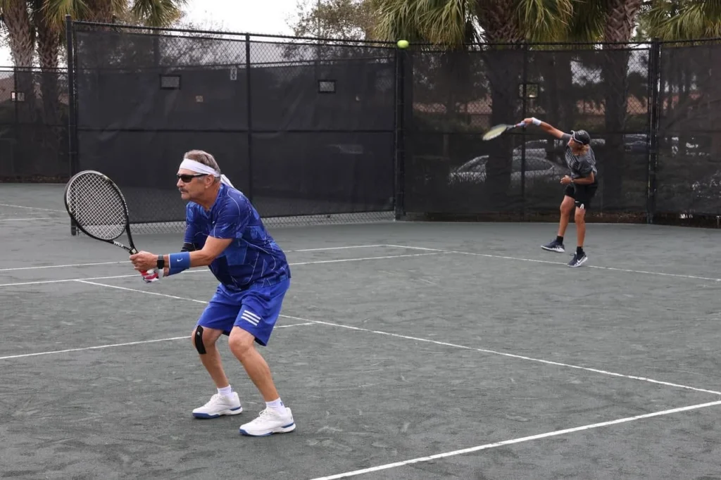 Residents playing doubles tennis on Har-Tru courts at Valencia Reserve